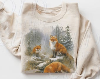 May include: Sand-colored sweatshirt featuring a detailed illustration of three foxes in a winter forest scene. The foxes have reddish-orange fur and are set against a backdrop of snow-covered ground and evergreen trees. The text "OLD SCHOOL CULT" is visible.