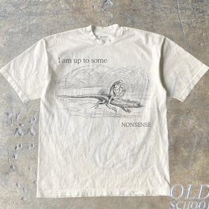 May include: A beige t-shirt with a black and white illustration of two lizards. The text "I am up to some nonsense" is printed on the shirt.