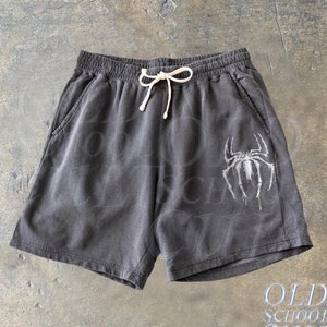 May include: Dark gray cotton shorts with a white spider graphic and a white drawstring. The shorts have two side pockets and a white "OLD SCHOOL CULT" text printed on the bottom right corner.