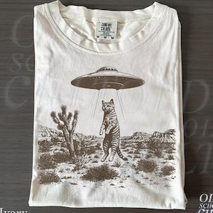 UFO猫ウエスタンTシャツ、コンフォートカラーズ®アイボリーシャツ、ヴィンテージエイリアングラフィックTシャツ、面白い宇宙猫トップス、レトロSFギフト
