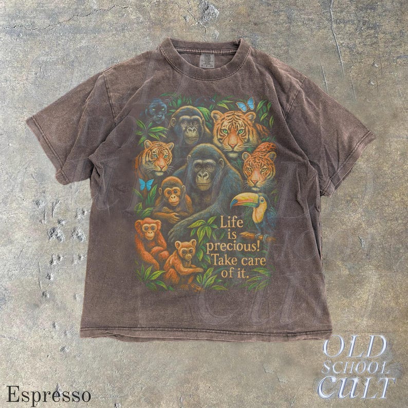 May include: Espresso-colored t-shirt featuring a vibrant jungle scene with gorillas, tigers, monkeys, and a toucan. The shirt includes the text "Life is precious! Take care of it." The shirt is from Old School Cult.
