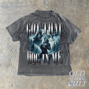 May include: A gray t-shirt with a distressed look features a graphic of two wolves howling at the moon. The text "GOT THAT DOG IN ME" is printed in silver lettering.