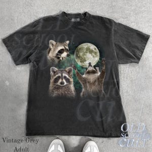May include: Vintage grey adult t-shirt featuring a graphic of three raccoons with a full moon in a night sky. The shirt has a crew neck and short sleeves. The text "OLD SCHOOL CULT" is printed on the bottom right.