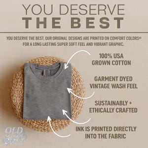 May include: A folded, gray t-shirt with a crew neck, displayed on a woven, circular mat. Text on the image reads "YOU DESERVE THE BEST" and details about the shirt's features, including "100% USA GROWN COTTON" and "GARMENT DYED VINTAGE WASH FEEL."