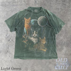 以下が含まれることがあります： 惑星を背景に3匹の猫が描かれた、ライトグリーンのTシャツ。猫はオレンジ、白黒、茶色です。Tシャツには「OLD SCHOOL CULT」と「Light Green」の文字がプリントされています。