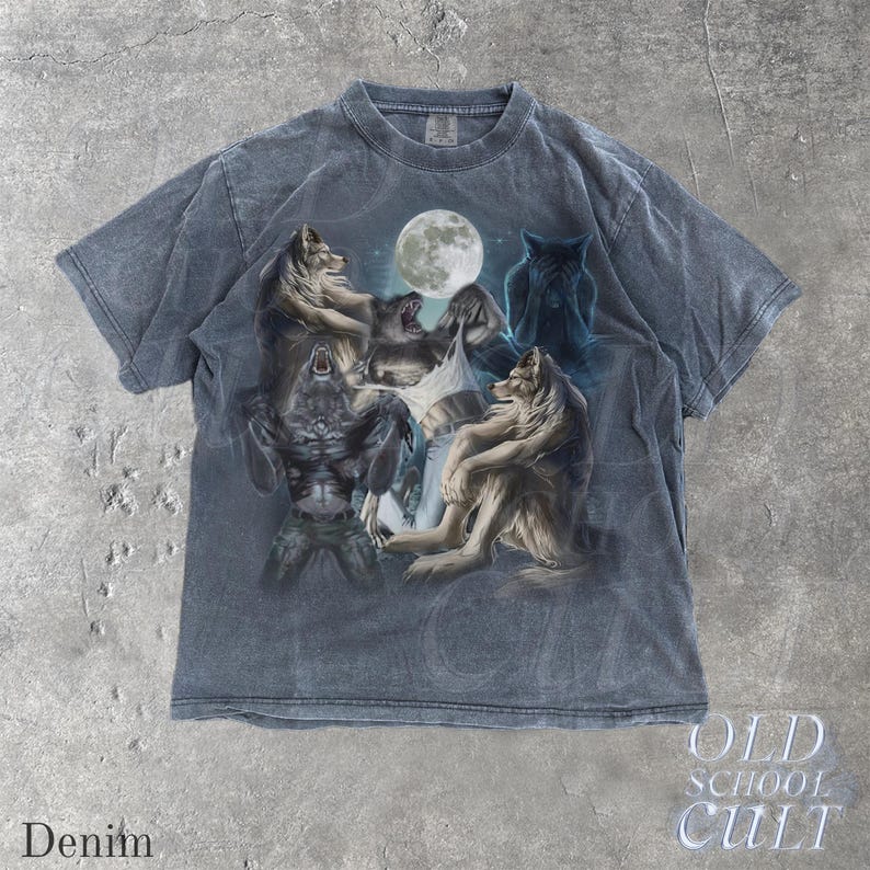 May include: Denim-colored t-shirt featuring a graphic of wolves and a werewolf under a full moon. The design includes various wolf poses and a mystical, fantasy theme. The text "OLD SCHOOL CULT" is visible.