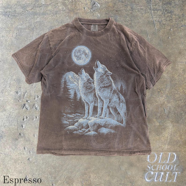 May include: Espresso-colored t-shirt featuring a graphic of two wolves howling at a full moon. The design includes a forest and starry sky. The shirt has a crew neck and short sleeves. The text "OLD SCHOOL CULT" is in the lower right corner.
