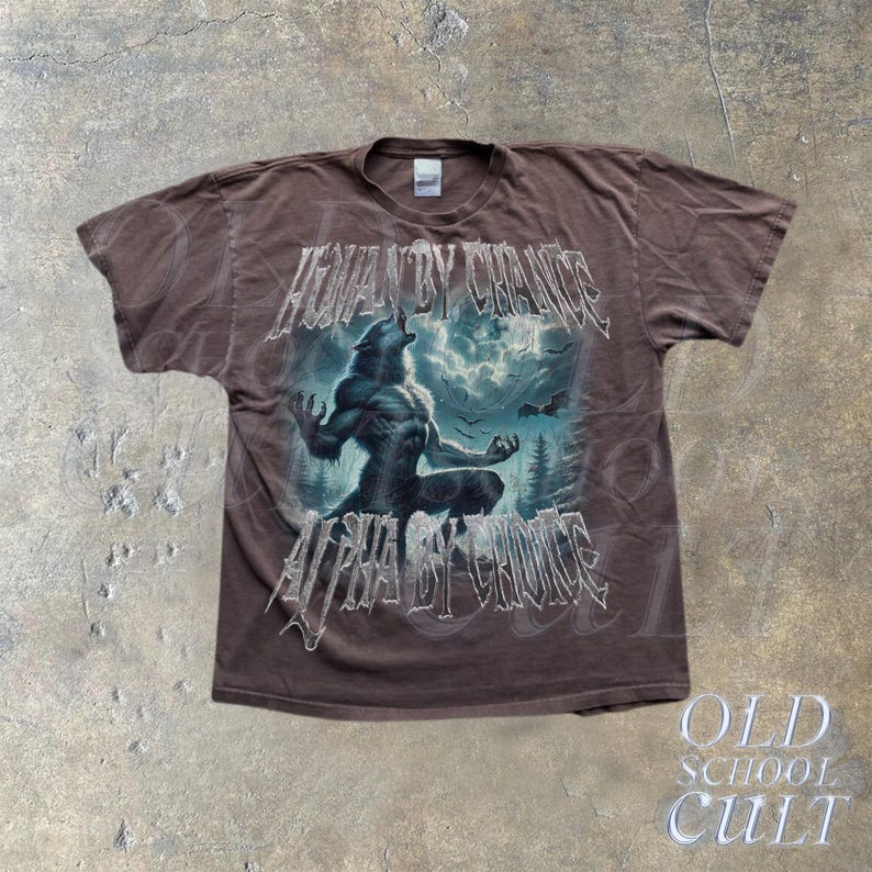 Puede incluir: Camiseta marr&oacute;n con un dise&ntilde;o de hombre lobo y el texto "HUMAN BY CHANCE, ALPHA BY CHOICE". El dise&ntilde;o incluye una escena de bosque y un cielo tormentoso. La camiseta tiene un aspecto vintage.
