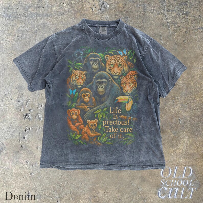 May include: A denim-colored t-shirt featuring a vibrant graphic of various jungle animals, including tigers, monkeys, and a gorilla, surrounded by lush green foliage. The shirt has the text "Life is precious! Take care of it."