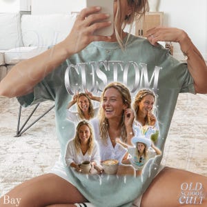 May include: Sage green t-shirt with the word "CUSTOM" in a silver, metallic font. The shirt features a collage of photos of a person, with the words "OLD SCHOOL CULT" and "Bay" printed on the shirt.