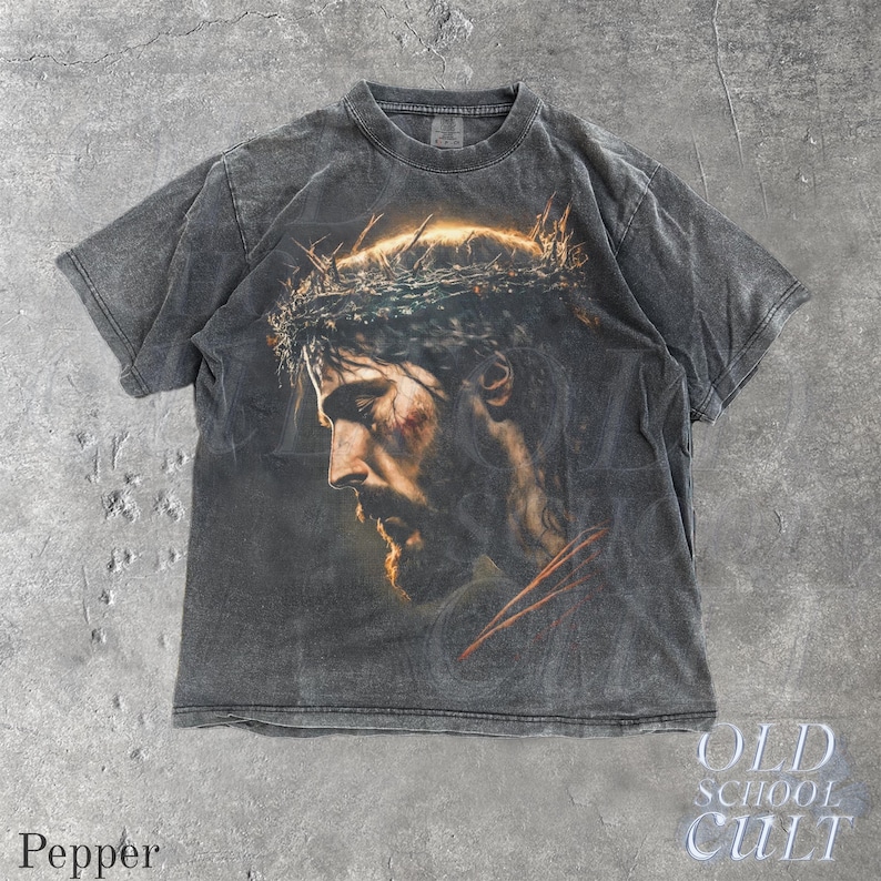 May include: Pepper-colored t-shirt featuring a detailed portrait of a man with a crown of thorns. The graphic is in shades of brown, gold, and red, set against a dark gray background. The text "OLD SCHOOL CULT" is visible.