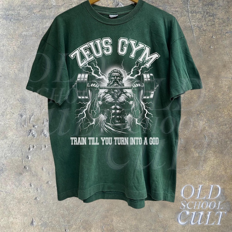 May include: Green t-shirt with a white graphic of a muscular figure lifting a barbell. The graphic includes the text "Zeus Gym" and "Train till you turn into a god."