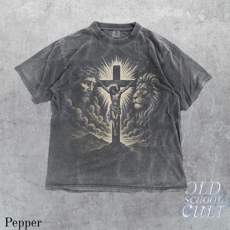 May include: Pepper-colored t-shirt featuring a graphic of Jesus on the cross, flanked by a lion and a man's face. The design is vintage-inspired, with a faded, distressed look. The shirt has short sleeves and a crew neck. The text "OLD SCHOOL CULT" is visible.