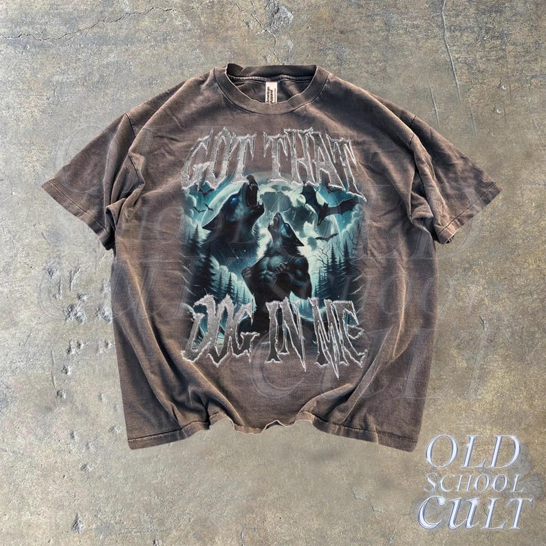 K&ouml;nnte beinhalten: Ein braunes T-Shirt mit einem grafischen Aufdruck von zwei W&ouml;lfen, die zum Mond heulen. Der Text "Got that dog in me" ist unter den W&ouml;lfen gedruckt.