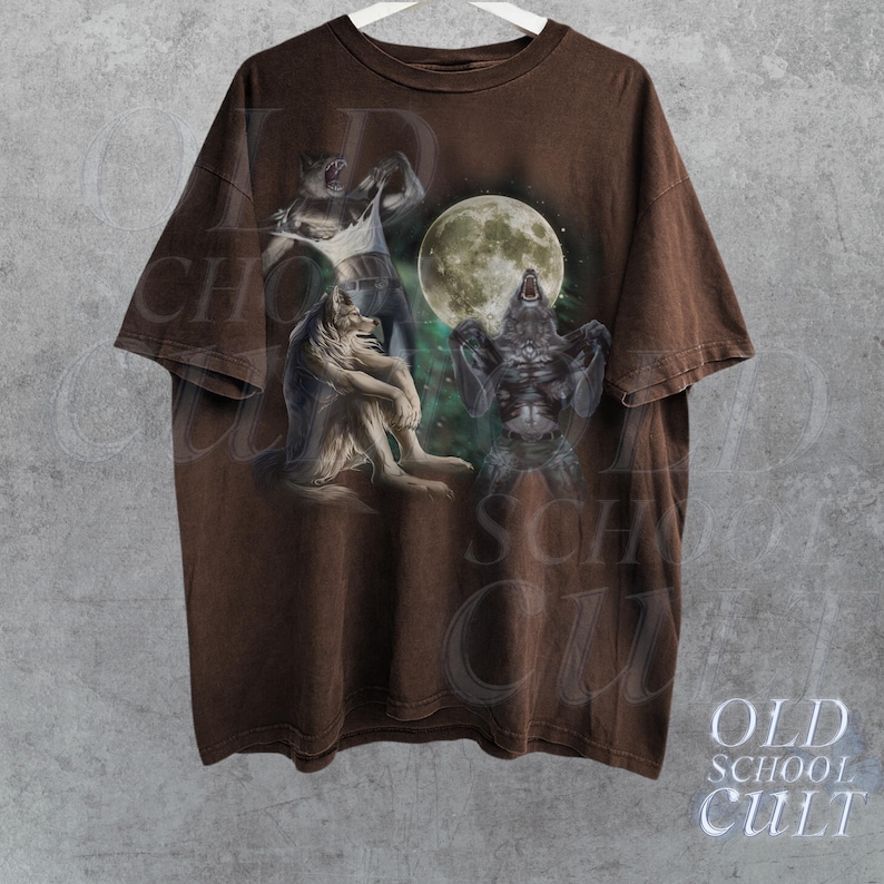 K&ouml;nnte beinhalten: Braunes T-Shirt mit einem Grafikdruck von drei Werw&ouml;lfen, die zum Mond heulen. Die Werw&ouml;lfe sind in einem realistischen Stil mit Fell und scharfen Z&auml;hnen dargestellt. Der Mond ist voll und hell, und der Hintergrund ist ein dunkler Wald.