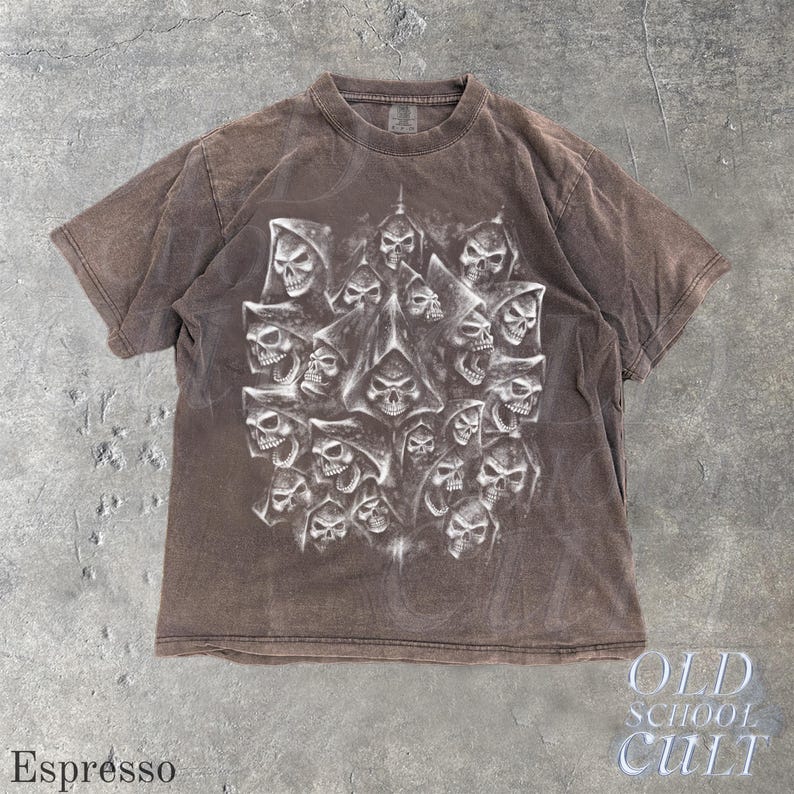 以下が含まれることがあります： エスプレッソ色のTシャツ。フード付きの頭蓋骨が多数描かれた詳細なグラフィックが特徴です。デザインは白とグレーの色合いを使用し、シャツの暗い背景と対照的です。「OLD SCHOOL CULT」の文字が右下に表示されています。