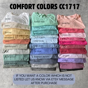 Peut inclure: Des piles de t-shirts pli&eacute;s de diff&eacute;rentes couleurs, dont blanc, ivoire et p&ecirc;che. L'image pr&eacute;sente une large gamme de teintes, du vert clair au noir, avec le texte "COMFORT COLORS CC1717" en haut. Le texte en bas dit "IF YOU WANT A COLOR WHICH IS NOT LISTED LET US KNOW VIA ETSY MESSAGE AFTER PURCHASE."
