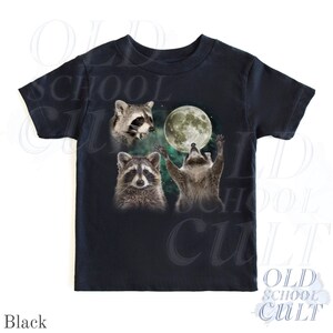 May include: Black t-shirt featuring a graphic of three raccoons and a full moon. One raccoon is looking up at the moon with its arms raised. The text "OLD SCHOOL CULT" is printed on the shirt.