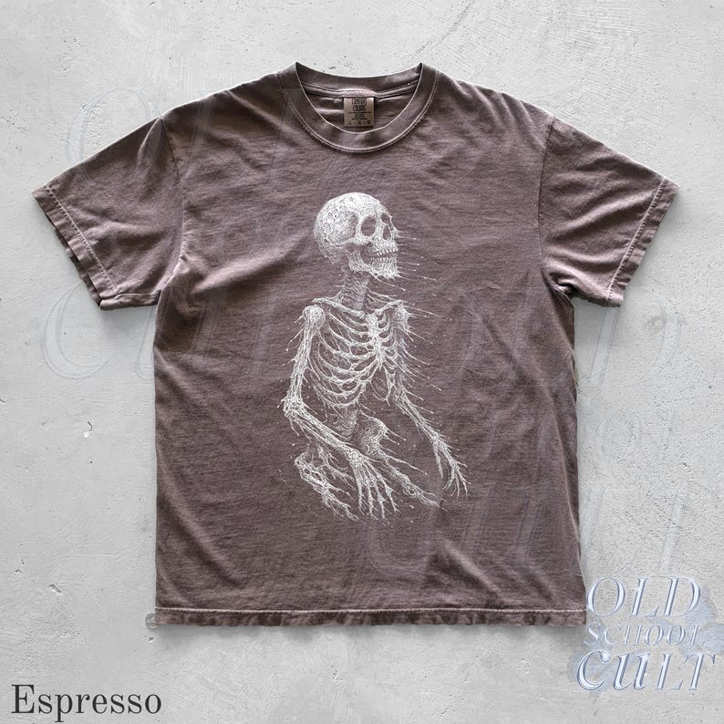 May include: Espresso-colored t-shirt featuring a detailed white skeleton graphic. The shirt has a crew neck and short sleeves. The text "OLD SCHOOL CULT" is visible in the lower right corner. The word "Espresso" is at the bottom left.
