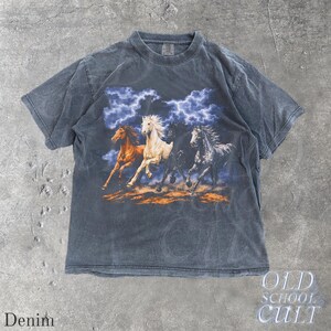May include: Denim-colored short-sleeve t-shirt featuring a graphic of four running horses with a stormy sky backdrop. The horses are in shades of brown, white, and black. The text "OLD SCHOOL CULT" is printed on the bottom right.