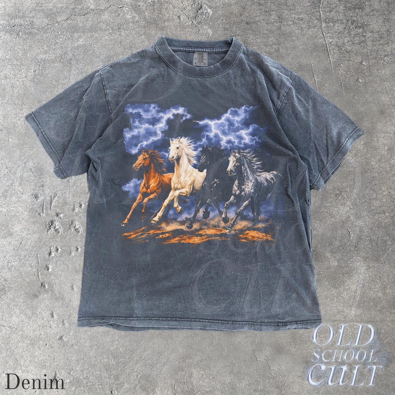 May include: Denim-colored short-sleeve t-shirt featuring a graphic of four running horses with a stormy sky backdrop. The horses are in shades of brown, white, and black. The text "OLD SCHOOL CULT" is printed on the bottom right.
