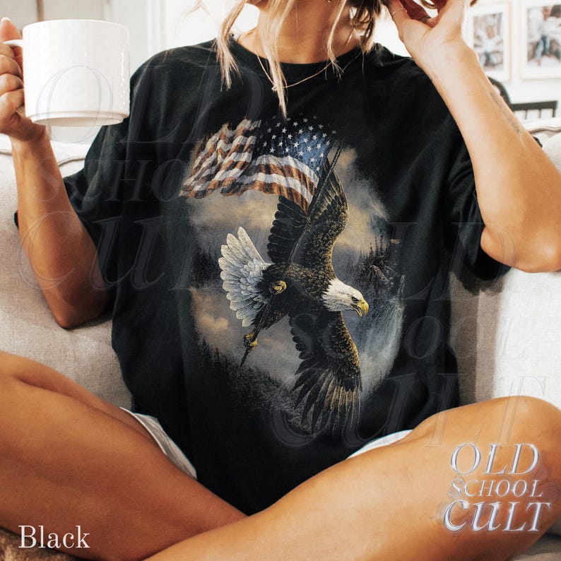 May include: Black t-shirt with a detailed graphic of a bald eagle soaring beneath an American flag. The shirt displays the text "OLD SCHOOL CULT" and the word "Black" at the bottom.