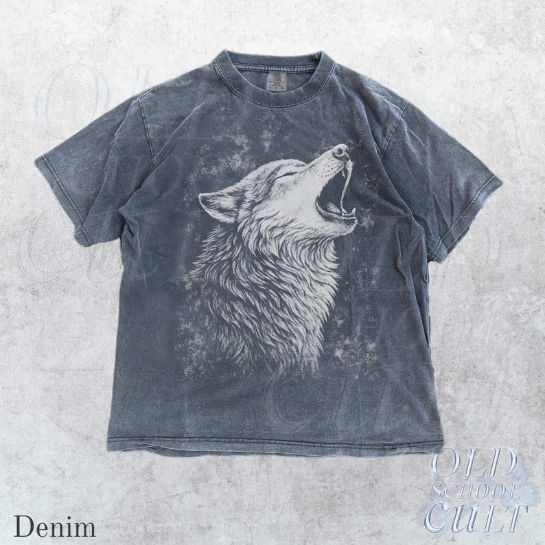 Puede incluir: Camiseta color denim con una detallada ilustraci&oacute;n blanca de un lobo aullando. La camiseta tiene un aspecto vintage y desgastado. El texto "Denim" est&aacute; en la parte inferior izquierda y "OLD SCHOOL CULT" en la parte inferior derecha.