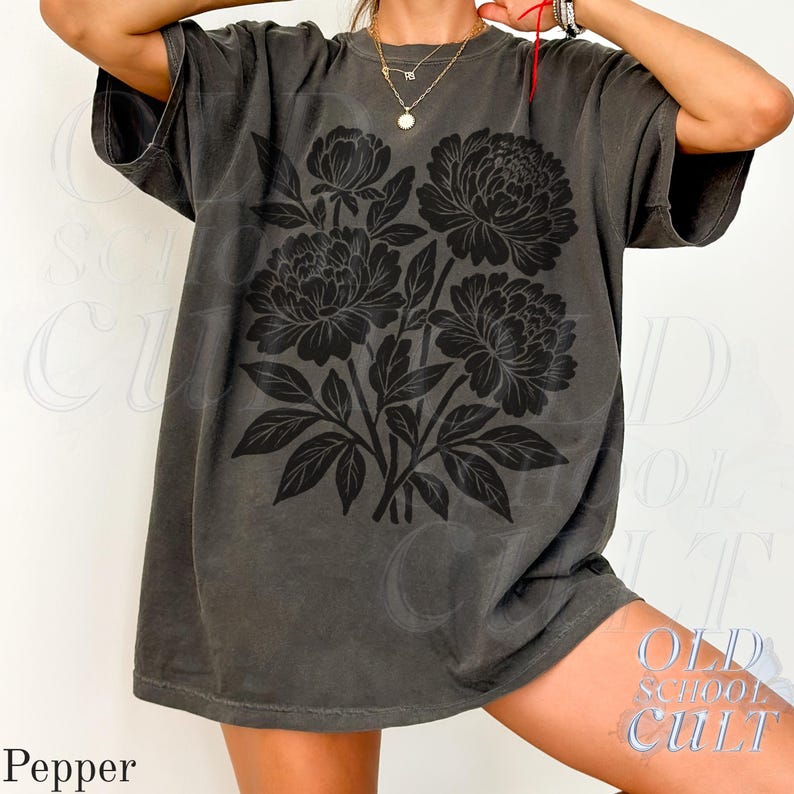 May include: A dark grey t-shirt with a black floral design. The graphic shows a bouquet of peonies and leaves. The shirt has a vintage, worn appearance. The word "Pepper" is printed at the bottom left.