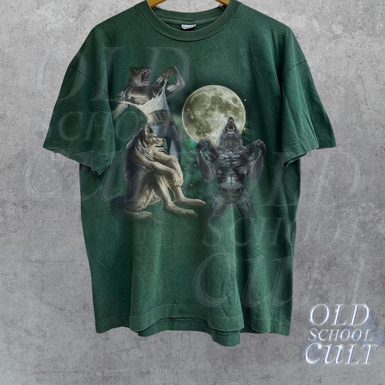 K&ouml;nnte beinhalten: Gr&uuml;nes T-Shirt mit einem Grafikdruck von drei Werw&ouml;lfen, die zum Mond heulen. Die Werw&ouml;lfe sind in einem realistischen Stil mit detailliertem Fell und scharfen Z&auml;hnen dargestellt.