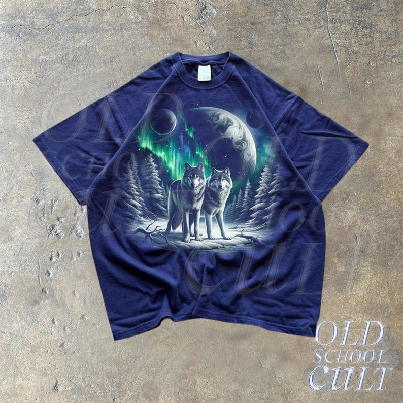 May include: A navy blue t-shirt with a graphic print of two wolves standing in a snowy forest under a green and blue aurora borealis. The graphic also includes a moon and stars.