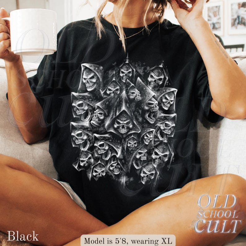 以下が含まれることがあります： 黒いTシャツ。フード付きのローブを着た多数の頭蓋骨の詳細なグラフィックが特徴です。デザインはシャツの中央に配置され、ゴシック様式です。「OLD SCHOOL CULT」の文字がシャツの右下にプリントされています。