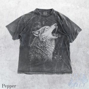 Puede incluir: Camiseta gris pimienta con una ilustraci&oacute;n blanca de un lobo aullando. El dise&ntilde;o est&aacute; sobre un fondo descolorido y texturizado. La camiseta tiene cuello redondo y mangas cortas. El texto "OLD SCHOOL CULT" es visible.