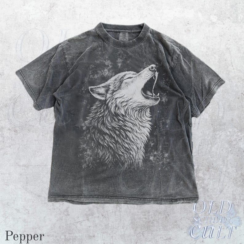 Puede incluir: Camiseta gris pimienta con una ilustraci&oacute;n blanca de un lobo aullando. El dise&ntilde;o est&aacute; sobre un fondo descolorido y texturizado. La camiseta tiene cuello redondo y mangas cortas. El texto "OLD SCHOOL CULT" es visible.