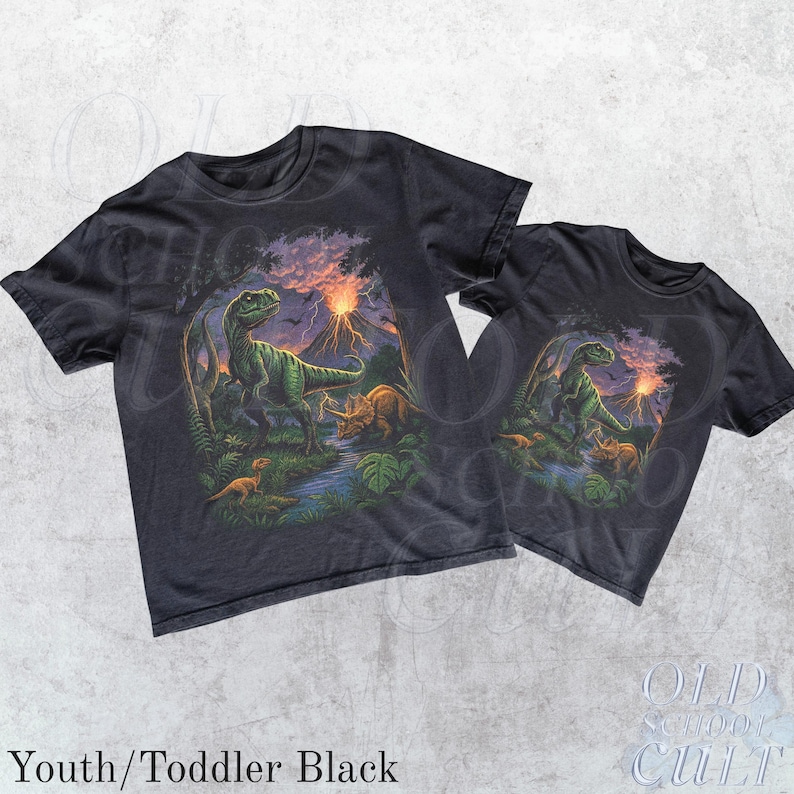 Op de afbeelding: Twee zwarte t-shirts met een dinosaurusafbeelding. Het ontwerp toont een groene Tyrannosaurus Rex, andere dinosaurussen, een rivier en een vulkaan onder een zonsonderganghemel. De tekst "Youth/Toddler Black" staat onderaan.
