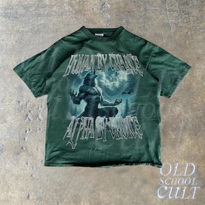 Puede incluir: Camiseta verde oscuro con un gr&aacute;fico de hombre lobo y el texto "HUMAN BY CHANCE, ALPHA BY CHOICE". El dise&ntilde;o incluye un lobo aullando a la luna, sobre un fondo de bosque. La camiseta tiene una est&eacute;tica vintage.