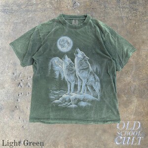 May include: Light green t-shirt featuring a graphic of two wolves howling at a full moon. The design includes a mountain range and forest. The shirt has the text "OLD SCHOOL CULT" and "Light Green".