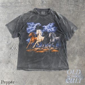 May include: Pepper-colored t-shirt featuring a graphic of four running horses under a stormy sky. The horses are in shades of brown, white, black, and gray. The shirt has a vintage, distressed look, with the text "OLD SCHOOL CULT" on the bottom right.