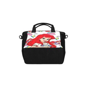 Puede incluir: Bolso tote negro con un gr&aacute;fico colorido de Ariel de La Sirenita. El bolso tiene un fondo blanco con ilustraciones de Ariel y arco&iacute;ris. Tiene dos asas negras y una base negra.