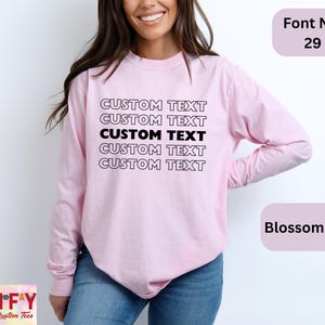 May include: A pink long-sleeved shirt with the text "CUSTOM TEXT" repeated five times in black. The shirt is shown on a model. The text "Font No. 29" and "Blossom Shirt" are also visible in the image.