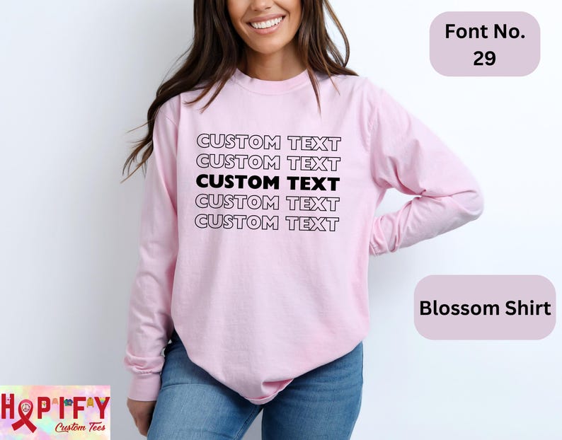 May include: A pink long-sleeved shirt with the text "CUSTOM TEXT" repeated five times in black. The shirt is shown on a model. The text "Font No. 29" and "Blossom Shirt" are also visible in the image.
