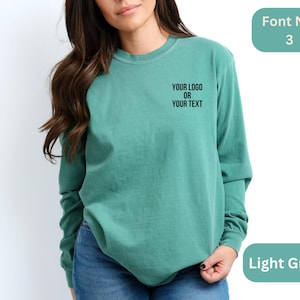May include: A light green long-sleeved t-shirt with the text "YOUR LOGO OR YOUR TEXT" in black.