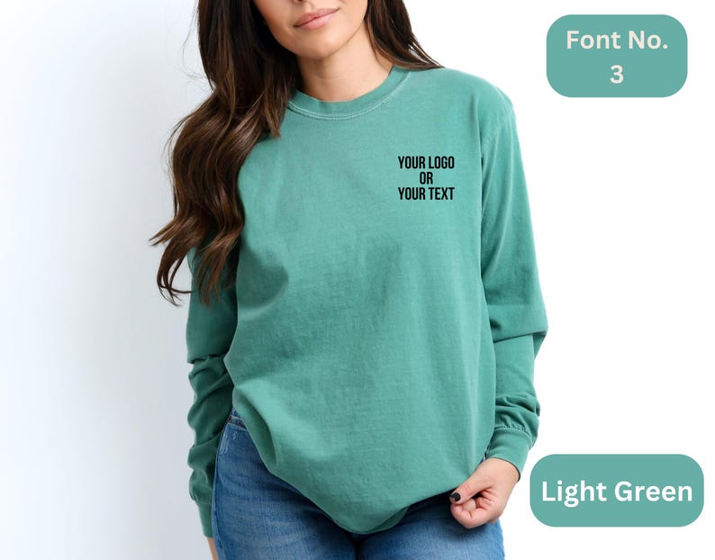 May include: A light green long-sleeved t-shirt with the text "YOUR LOGO OR YOUR TEXT" in black.