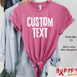 May include: A pink t-shirt with the text "CUSTOM TEXT" in white. The shirt is made of a soft, comfortable material and is perfect for everyday wear.