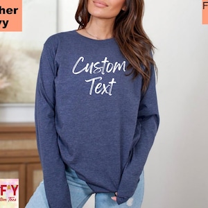 May include: A heather navy long-sleeve shirt with the text "Custom Text" in white cursive font. The shirt is made of a soft, comfortable material and is perfect for everyday wear.