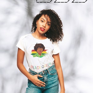 Peut inclure: Une femme portant un t-shirt blanc avec un graphique d'une femme avec des cheveux crépus portant des lunettes et un motif jaune, vert et rouge. Le graphique est sur un contour brun du continent africain. Le texte "BLACK QUEEN" est imprimé sous le graphique.