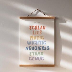 May include: A framed print with the text "Ich Bin..." at the top and a list of German words in rainbow colors: "Schlau", "Lieb", "Mutig", "Wichtig", "Neugierig", "Stark", "Genug".