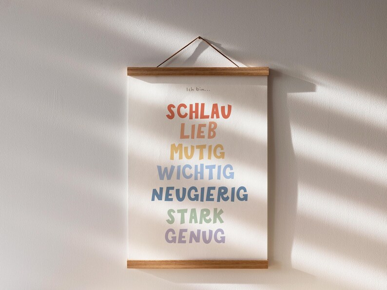 May include: A framed print with the text "Ich Bin..." at the top and a list of German words in rainbow colors: "Schlau", "Lieb", "Mutig", "Wichtig", "Neugierig", "Stark", "Genug".