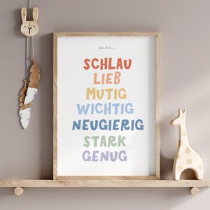 May include: A framed print with the text "Ich bin..." followed by a list of German words in rainbow colors: "Schlau", "Lieb", "Mutig", "Wichtig", "Neugierig", "Stark", "Genug". The print is on a wooden shelf with a wooden rabbit and a wooden giraffe figurine.