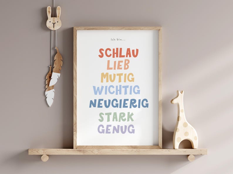 May include: A framed print with the text "Ich bin..." followed by a list of German words in rainbow colors: "Schlau", "Lieb", "Mutig", "Wichtig", "Neugierig", "Stark", "Genug". The print is on a wooden shelf with a wooden rabbit and a wooden giraffe figurine.