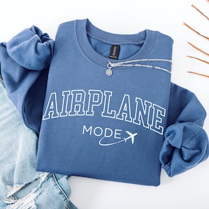 May include: A blue sweatshirt with the text "AIRPLANE MODE" in white with a small airplane graphic. The sweatshirt is folded and laid on a white surface.